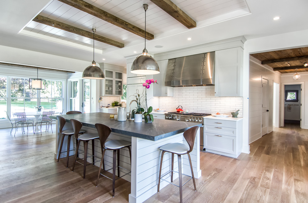Design ideas for a large country galley open plan kitchen in New York with recessed-panel cabinets, white cabinets, white splashback, subway tile splashback, stainless steel appliances, with island, soapstone benchtops and dark hardwood floors.
