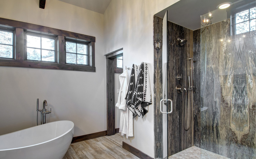 Inspiration for a large country master bathroom in Denver with a freestanding tub, an alcove shower, brown tile, stone slab, white walls, light hardwood floors, brown floor and a hinged shower door.