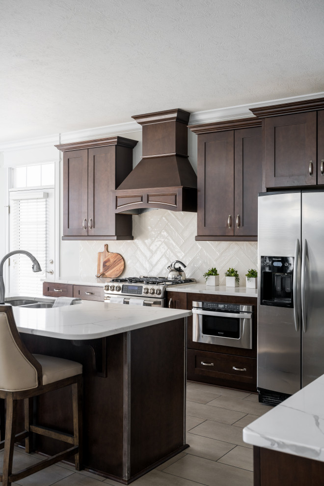 Mid-sized modern l-shaped separate kitchen in Indianapolis with an undermount sink, shaker cabinets, brown cabinets, marble benchtops, subway tile splashback, stainless steel appliances, with island and white benchtop.