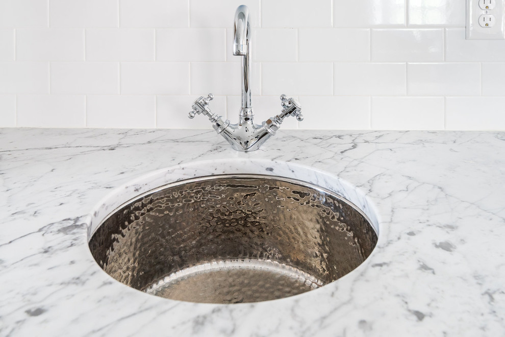 Inspiration for a transitional dark wood floor kitchen remodel in Richmond with a farmhouse sink, shaker cabinets, white cabinets, marble countertops, white backsplash, subway tile backsplash, stainless steel appliances and an island