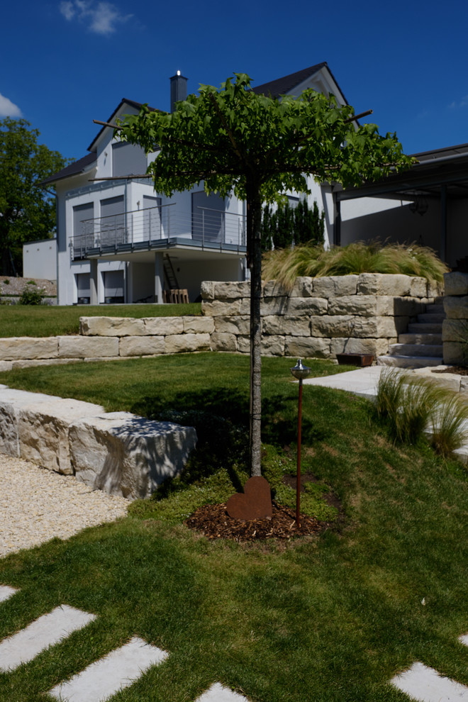 Weitläufiger Garten mit Mauern und Wegen aus Naturstein Modern