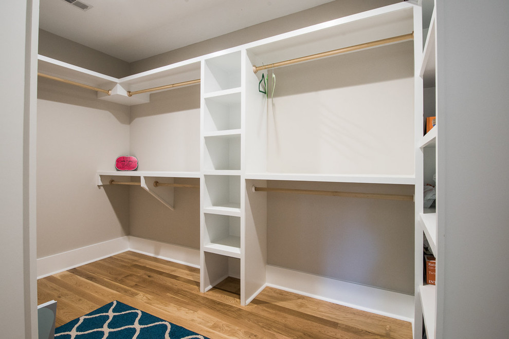 Photo of a large traditional gender-neutral walk-in wardrobe in Charleston with open cabinets, white cabinets and medium hardwood floors.