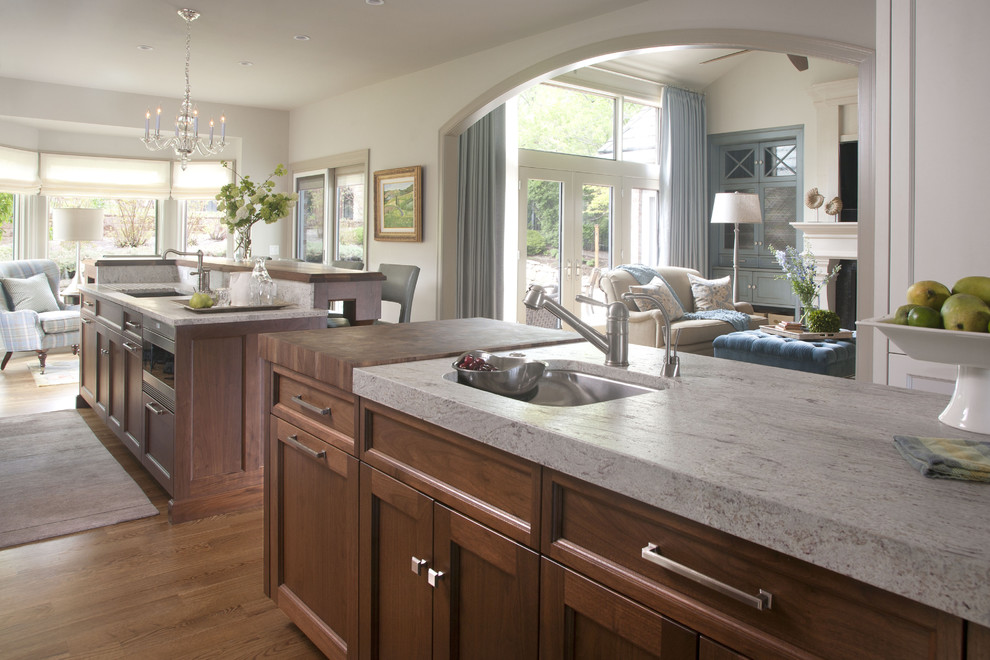 This is an example of a transitional open plan kitchen in Denver with an undermount sink, recessed-panel cabinets, dark wood cabinets and granite benchtops.