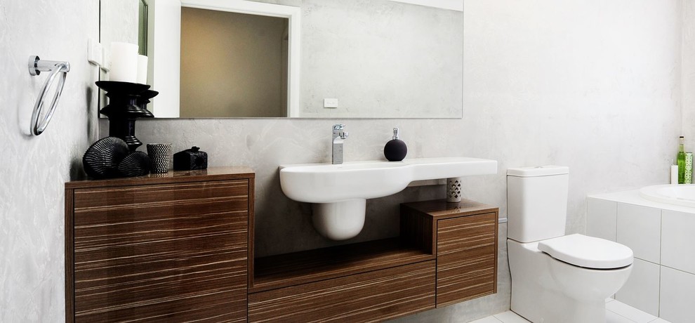 Photo of a small industrial master bathroom in Central Coast with a wall-mount sink, furniture-like cabinets, dark wood cabinets, laminate benchtops, a drop-in tub, a double shower, a one-piece toilet, gray tile, ceramic tile, grey walls and porcelain floors.