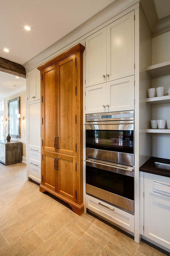 Inspiration for a large transitional galley ceramic tile eat-in kitchen remodel in Boston with an undermount sink, recessed-panel cabinets, white cabinets, wood countertops, white backsplash, stainless steel appliances and an island