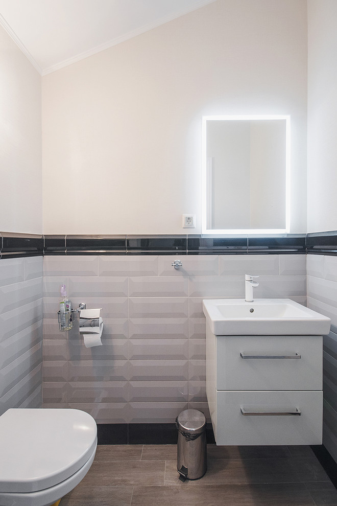 This is an example of a small contemporary powder room in Moscow with flat-panel cabinets, a two-piece toilet, white walls and ceramic floors.