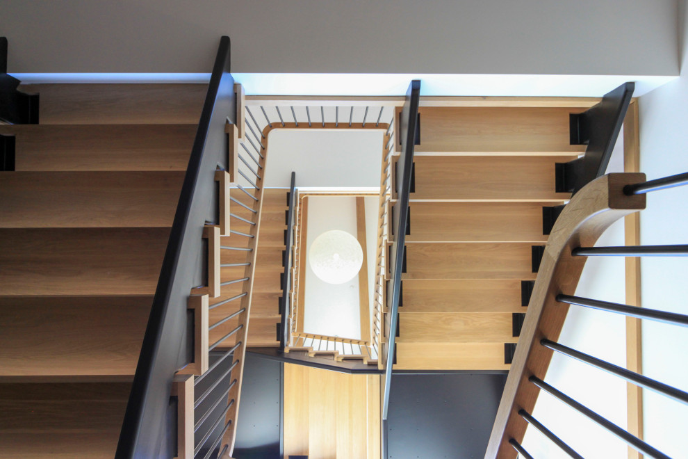 Réalisation d'un très grand escalier flottant minimaliste avec des marches en bois, un garde-corps en matériaux mixtes et du lambris de bois.