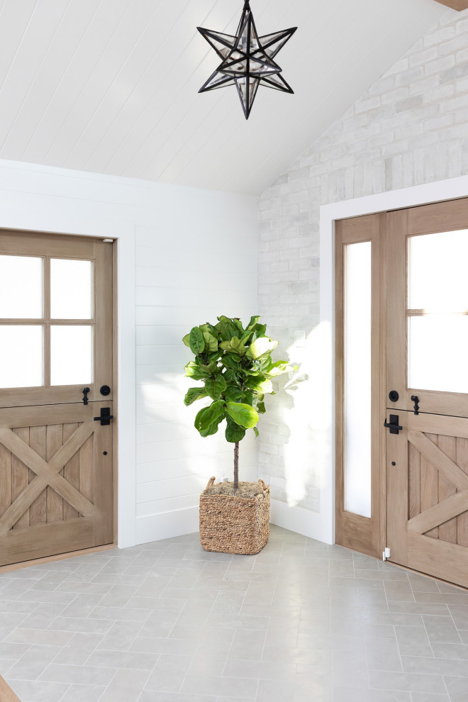 Mid-sized farmhouse limestone floor, green floor, shiplap ceiling and shiplap wall entryway photo in Orange County with white walls and a light wood front door