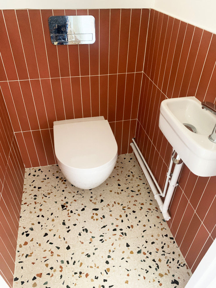 Ispirazione per un bagno di servizio minimal di medie dimensioni con WC sospeso, piastrelle marroni, piastrelle in ceramica, pareti bianche, pavimento alla veneziana, lavabo sospeso e pavimento multicolore