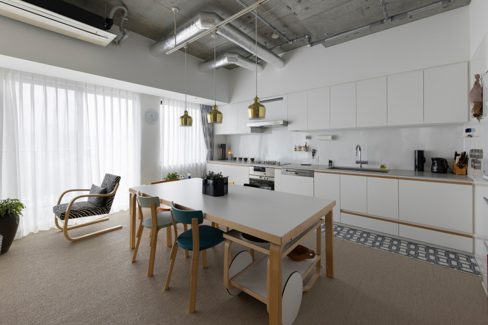 This is an example of an industrial single-wall open plan kitchen in Tokyo with an undermount sink, flat-panel cabinets, white cabinets, stainless steel appliances, carpet, no island, beige floor and grey benchtop.