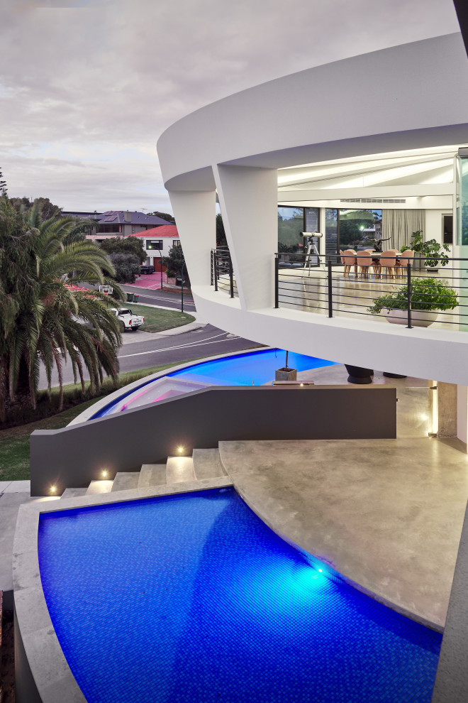 Inspiration for an expansive contemporary front yard custom-shaped lap pool in Perth with a hot tub and natural stone pavers.