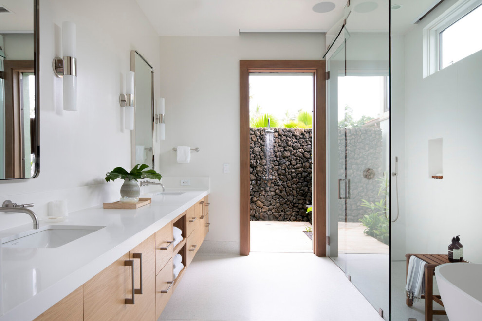 This is an example of a tropical master bathroom in Los Angeles with flat-panel cabinets, medium wood cabinets, a corner shower, white tile, white walls, an undermount sink, white floor, a hinged shower door, white benchtops, a niche, a double vanity and a floating vanity.