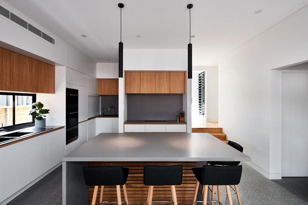 Design ideas for a contemporary l-shaped kitchen in Sydney with a double-bowl sink, flat-panel cabinets, white cabinets, grey splashback, with island, grey floor and grey benchtop.