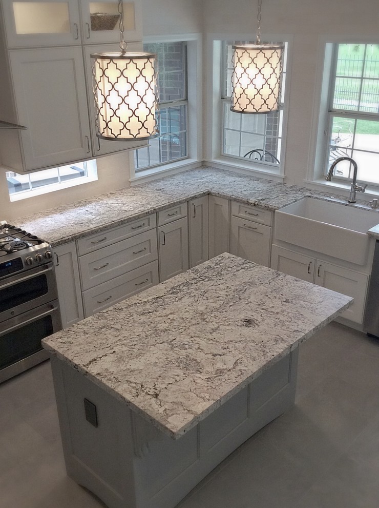 This is an example of a mid-sized transitional u-shaped eat-in kitchen in Houston with a farmhouse sink, recessed-panel cabinets, white cabinets, granite benchtops, white splashback, stone tile splashback, stainless steel appliances, ceramic floors and with island.