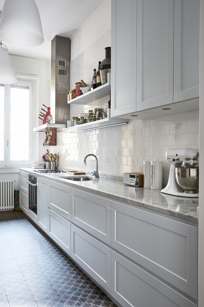 Inspiration for a mid-sized transitional single-wall kitchen in Milan with an undermount sink, shaker cabinets, white cabinets, white splashback, subway tile splashback, stainless steel appliances, multi-coloured floor and grey benchtop.