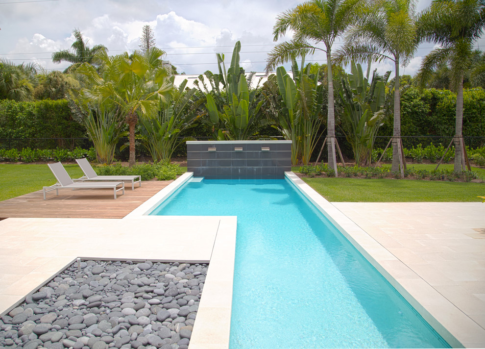 This is an example of a mid-sized contemporary backyard rectangular lap pool in Miami with a water feature and tile.