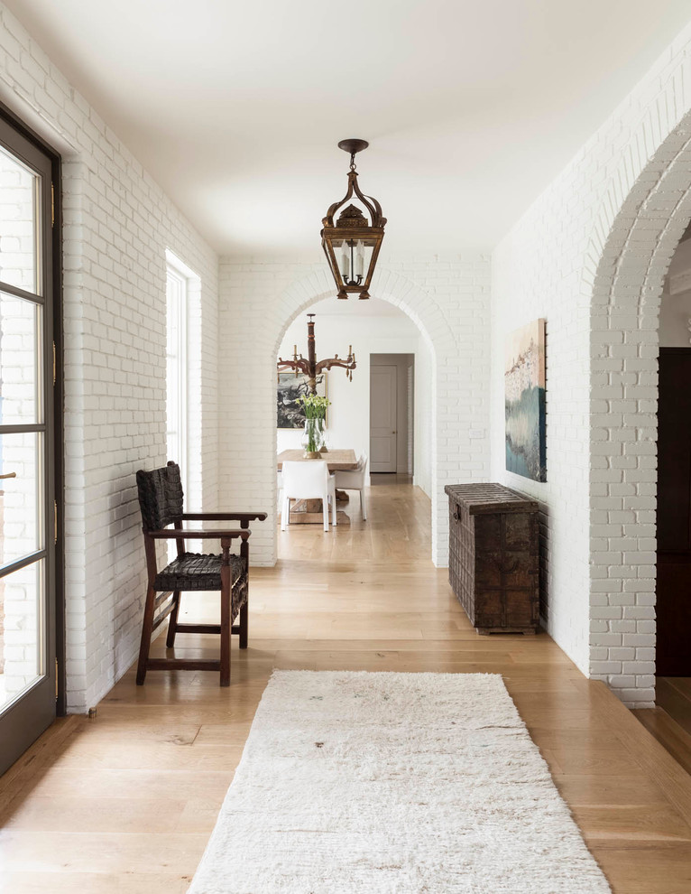 Transitional entry hall in Dallas with white walls, light hardwood floors and a glass front door.