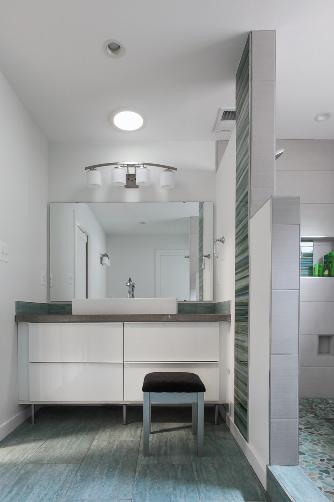 Photo of a mid-sized contemporary master bathroom in DC Metro with a vessel sink, flat-panel cabinets, white cabinets, engineered quartz benchtops, an alcove shower, gray tile, pebble tile, white walls, porcelain floors and a two-piece toilet.