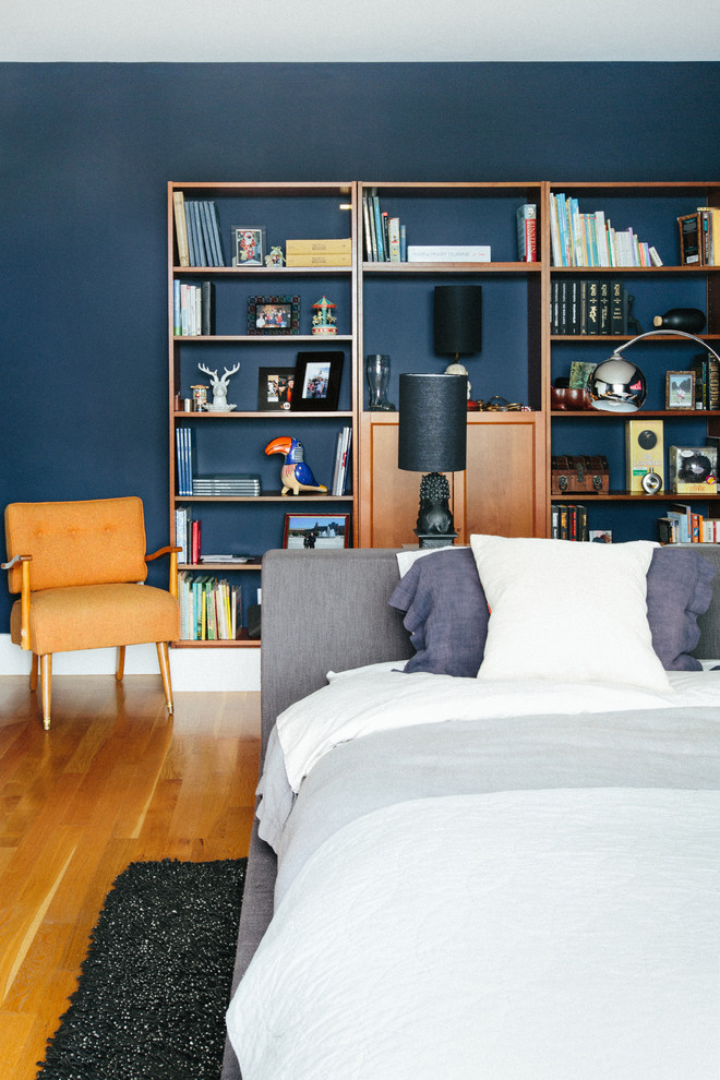 This is an example of a contemporary master bedroom in San Francisco with blue walls and light hardwood floors.
