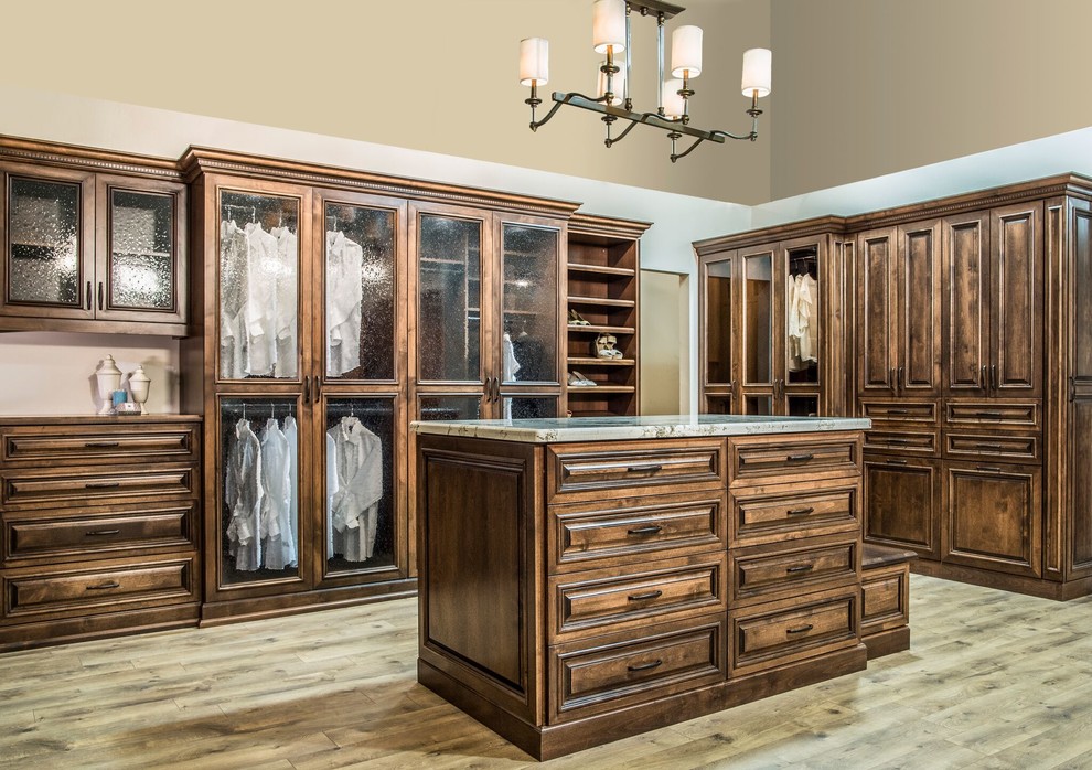 This is an example of a large traditional gender-neutral walk-in wardrobe in San Diego with beaded inset cabinets, dark wood cabinets, medium hardwood floors and beige floor.