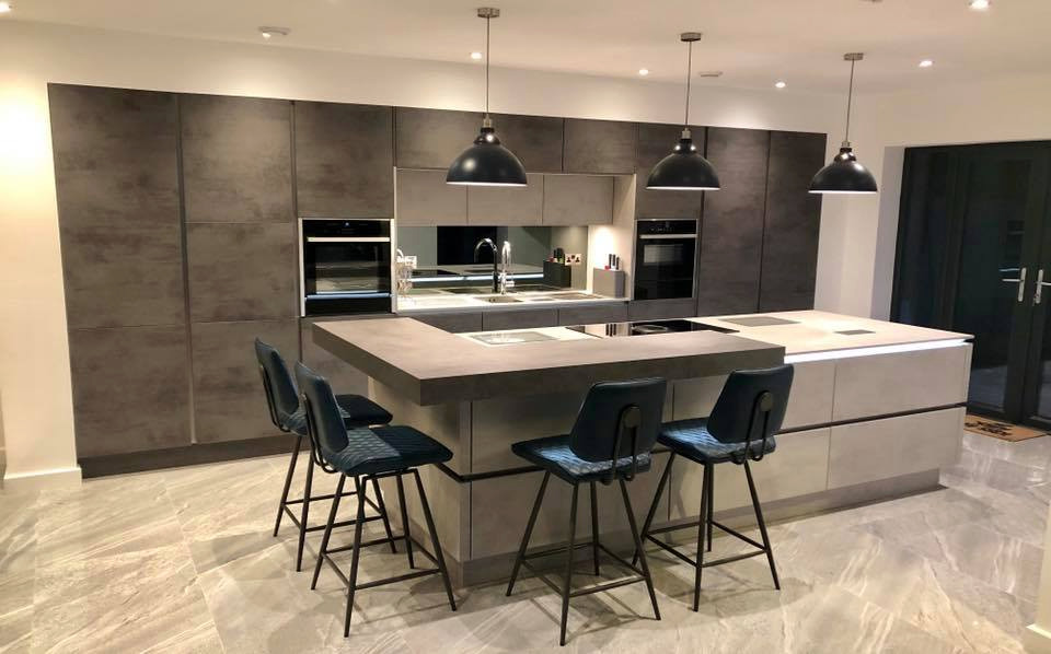 Photo of a large contemporary single-wall eat-in kitchen in Cheshire with grey cabinets, grey splashback, mirror splashback, panelled appliances, porcelain floors, with island, grey floor, grey benchtop and a drop-in sink.
