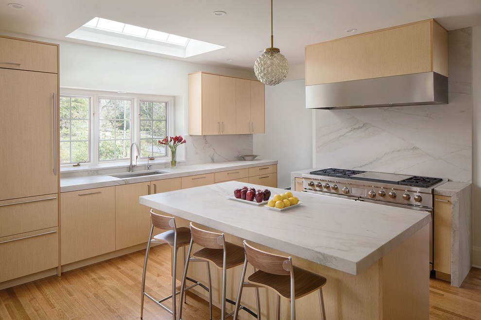 This is an example of a contemporary kitchen in Newark with an undermount sink, flat-panel cabinets, light wood cabinets, white splashback, light hardwood floors, with island and panelled appliances.