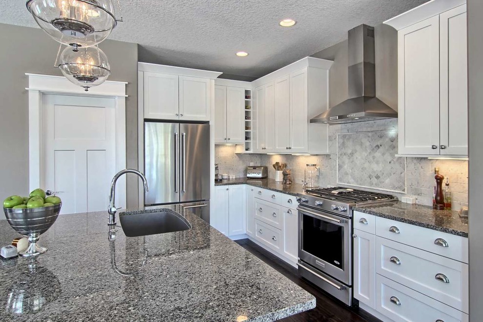 Example of a mid-sized transitional l-shaped dark wood floor open concept kitchen design with a single-bowl sink, shaker cabinets, white cabinets, granite countertops, gray backsplash, stone tile backsplash, stainless steel appliances and an island
