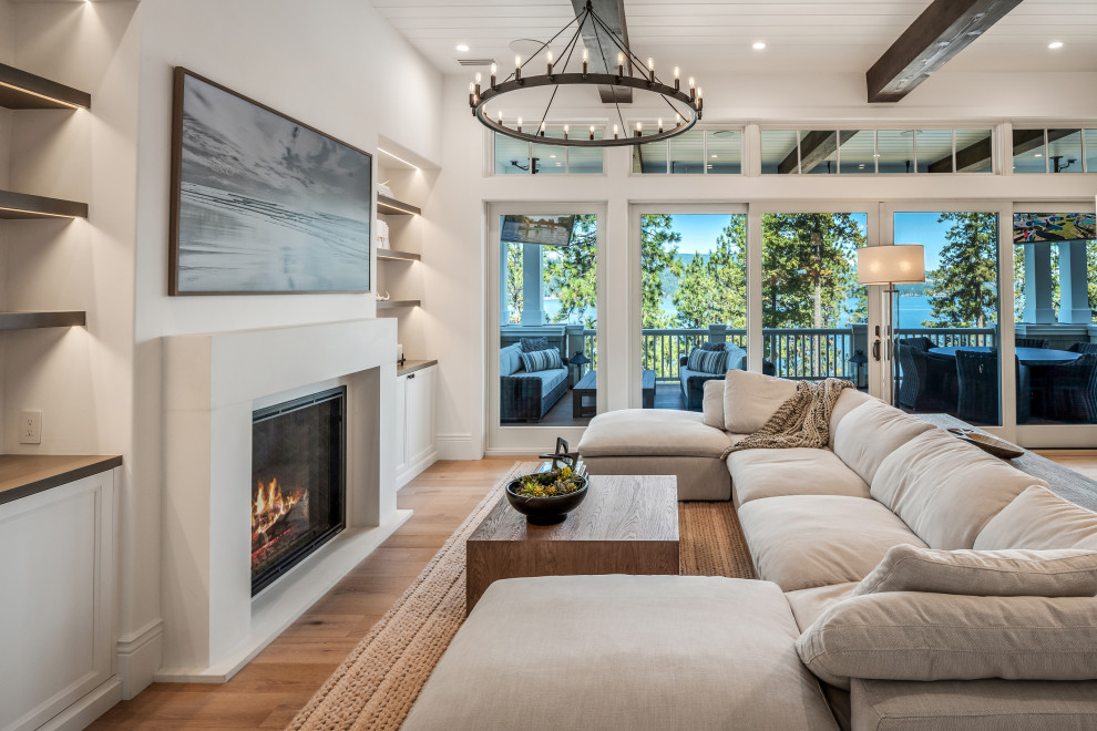 Inspiration for an expansive transitional open concept family room in San Francisco with white walls, light hardwood floors, a standard fireplace, a concrete fireplace surround, a wall-mounted tv, beige floor and exposed beam.