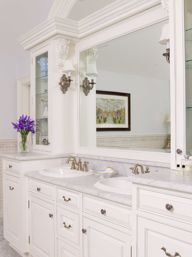 This is an example of a large traditional master bathroom in New York with raised-panel cabinets, white cabinets, white walls and an undermount sink.