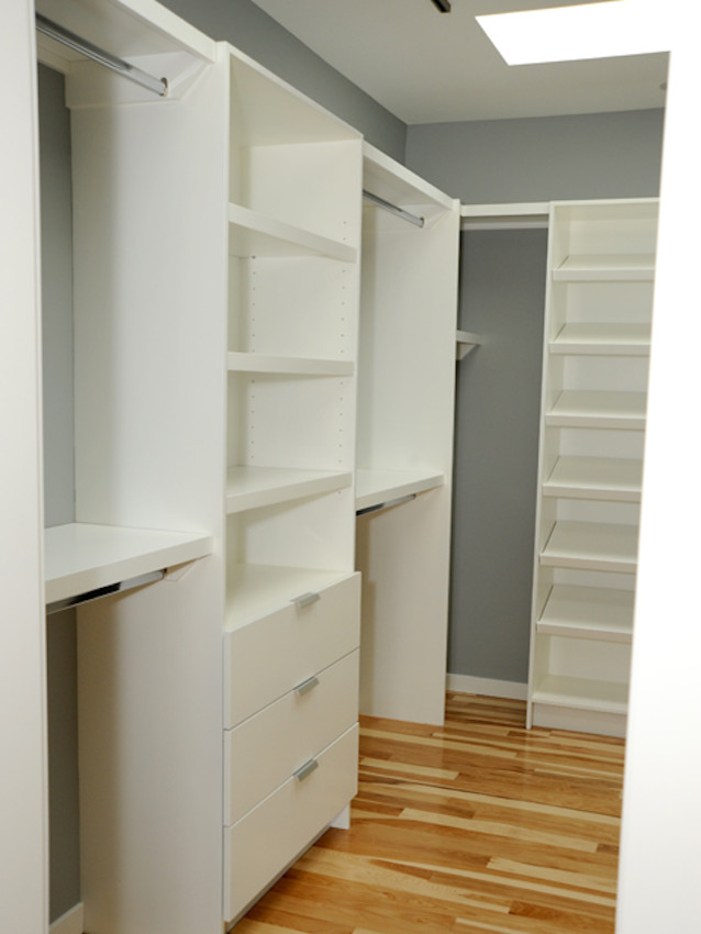 This is an example of a contemporary gender-neutral walk-in wardrobe in Calgary with open cabinets, white cabinets and light hardwood floors.