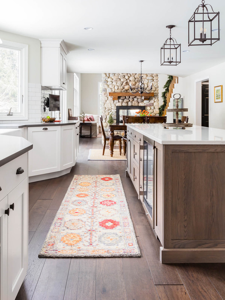 Transitional l-shaped eat-in kitchen photo in Providence with a farmhouse sink, shaker cabinets, white cabinets, quartzite countertops, white backsplash, subway tile backsplash, stainless steel appliances and an island