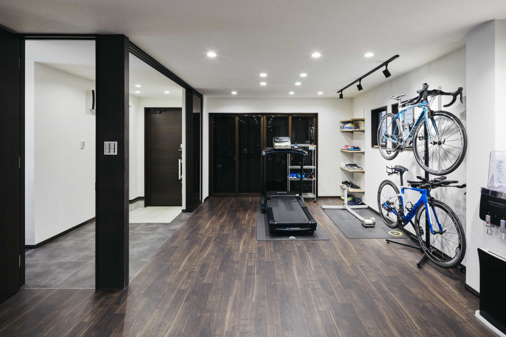 Design ideas for a mid-sized home weight room in Nagoya with white walls, dark hardwood floors and brown floor.