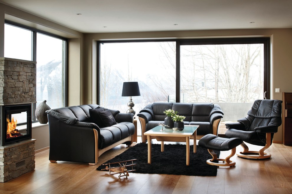 Inspiration for a mid-sized scandinavian open concept family room in Milwaukee with brown walls, medium hardwood floors, a standard fireplace, a stone fireplace surround, no tv and brown floor.