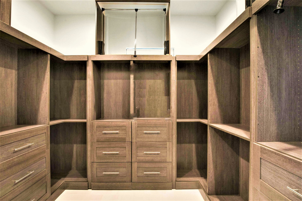 This is an example of a large modern women's storage and wardrobe in Austin with shaker cabinets, dark wood cabinets, porcelain floors and white floor.