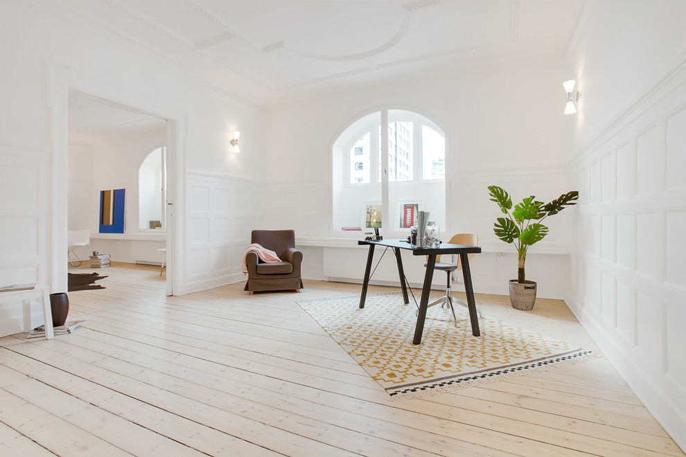 Photo of a scandinavian home office in Copenhagen with white walls, light hardwood floors and a freestanding desk.