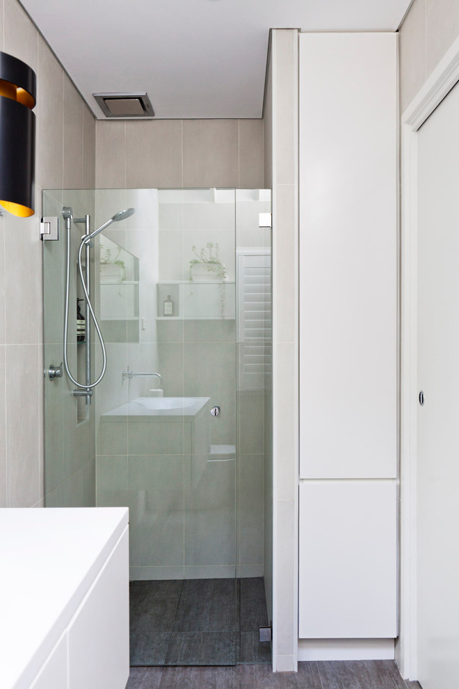 Mid-sized contemporary 3/4 bathroom in Sydney with flat-panel cabinets, white cabinets, an alcove shower, a one-piece toilet, beige tile, ceramic tile, beige walls, ceramic floors, an integrated sink, solid surface benchtops, brown floor and a hinged shower door.