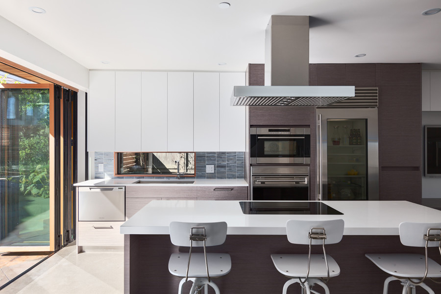 Contemporary open plan kitchen in Vancouver with an undermount sink, flat-panel cabinets, dark wood cabinets, quartz benchtops, grey splashback, stone tile splashback, stainless steel appliances and with island.