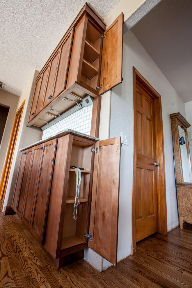 Inspiration for a mid-sized rustic u-shaped medium tone wood floor and brown floor enclosed kitchen remodel in Omaha with an undermount sink, shaker cabinets, dark wood cabinets, granite countertops, beige backsplash, travertine backsplash, stainless steel appliances, an island and multicolored countertops