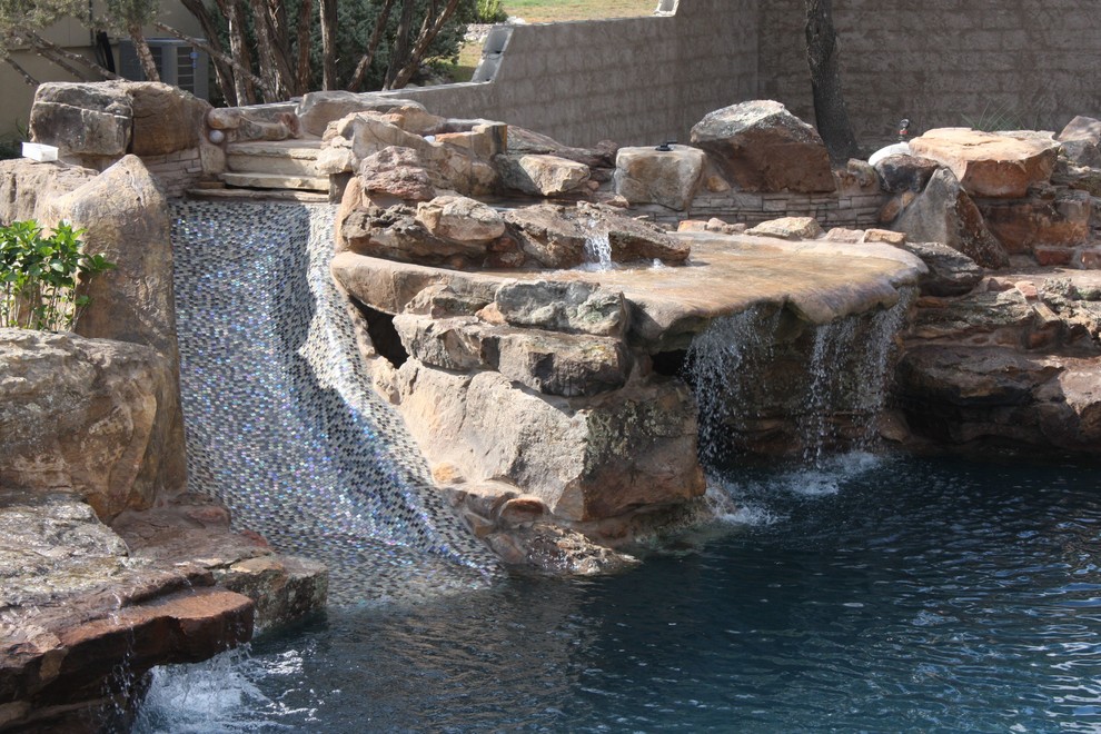 Mid-sized country backyard custom-shaped natural pool in Austin with a water feature and brick pavers.