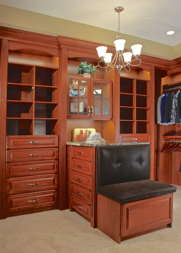 Large traditional walk-in wardrobe in Chicago with raised-panel cabinets, medium wood cabinets and travertine floors.