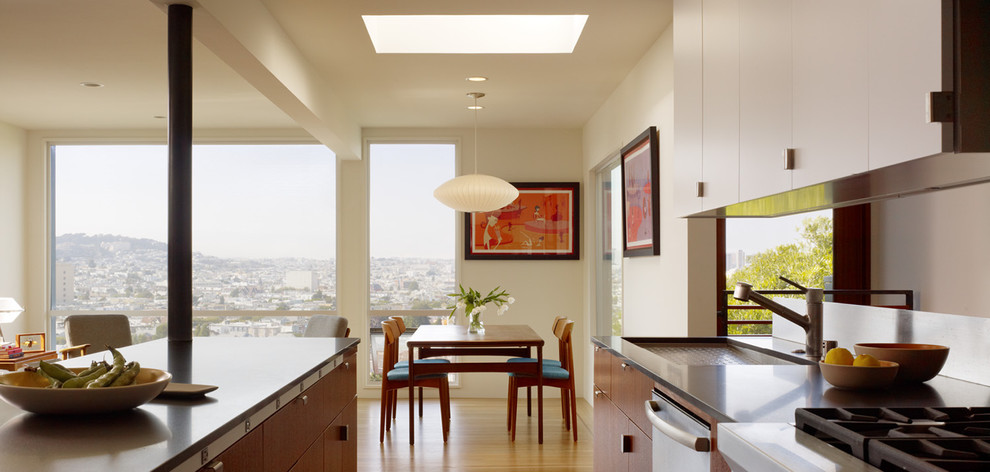 Inspiration for a mid-sized modern galley open plan kitchen in San Francisco with an undermount sink, flat-panel cabinets, medium wood cabinets, granite benchtops, stainless steel appliances, light hardwood floors and with island.
