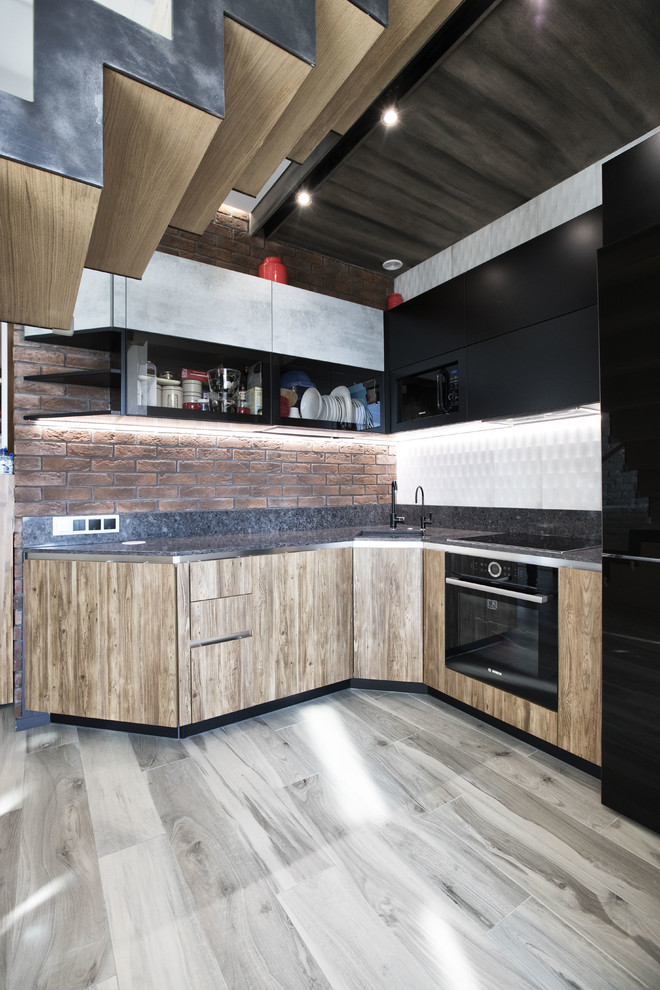 This is an example of a contemporary l-shaped eat-in kitchen in Moscow with an undermount sink, flat-panel cabinets, medium wood cabinets, brown splashback, brick splashback, black appliances, no island and grey floor.