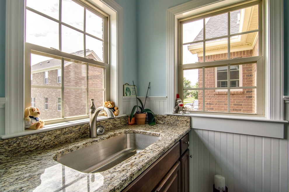 Inspiration for a mid-sized traditional single-wall utility room in Nashville with an undermount sink, raised-panel cabinets, dark wood cabinets, granite benchtops, blue walls and ceramic floors.