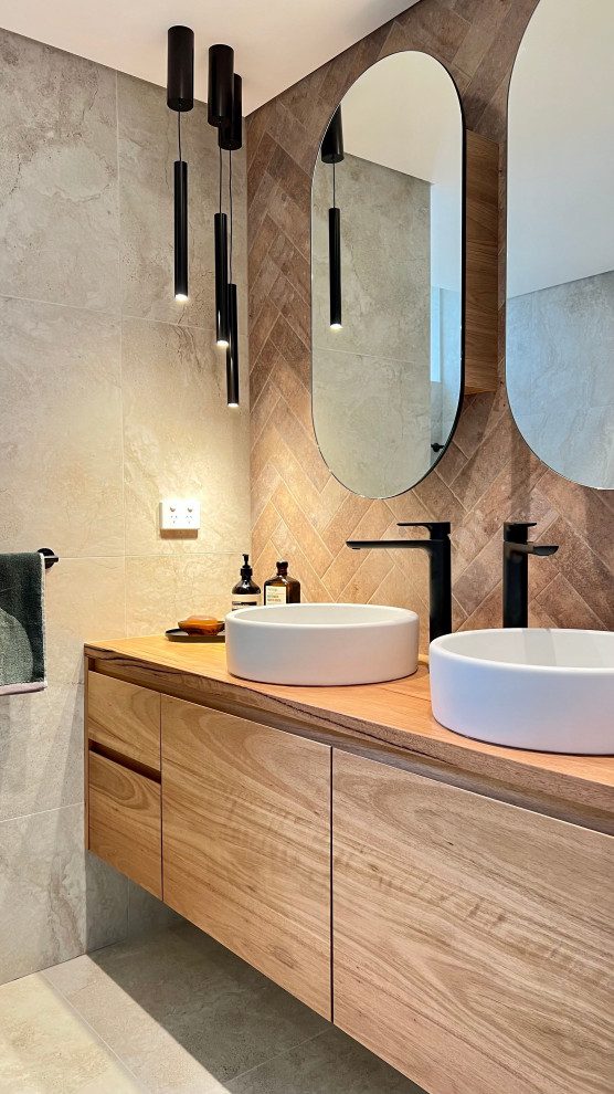 Photo of a small mediterranean bathroom in Sydney with flat-panel cabinets, brown cabinets, a freestanding tub, a curbless shower, a wall-mount toilet, beige tile, ceramic tile, beige walls, ceramic floors, a drop-in sink, wood benchtops, beige floor, a hinged shower door, brown benchtops, a double vanity and a floating vanity.