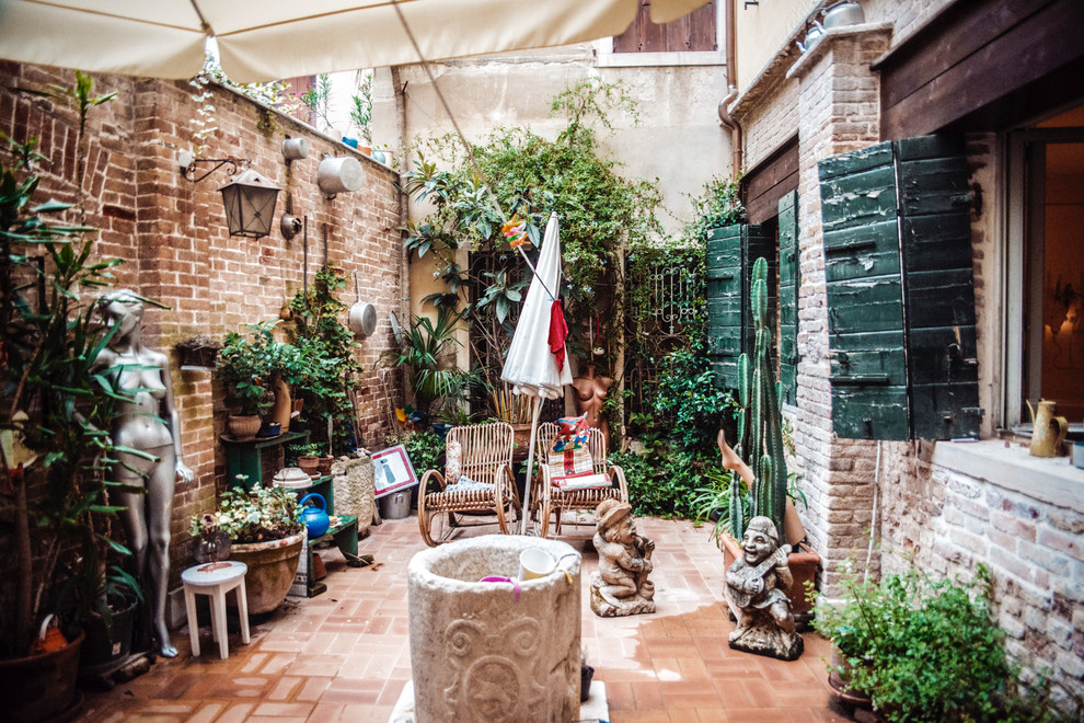 Inspiration for a country courtyard patio in Venice with brick pavers and an awning.