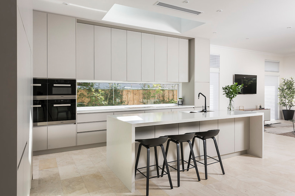 Design ideas for a large contemporary galley open plan kitchen in Perth with an undermount sink, grey cabinets, quartz benchtops, window splashback, stainless steel appliances, travertine floors, with island and beige floor.
