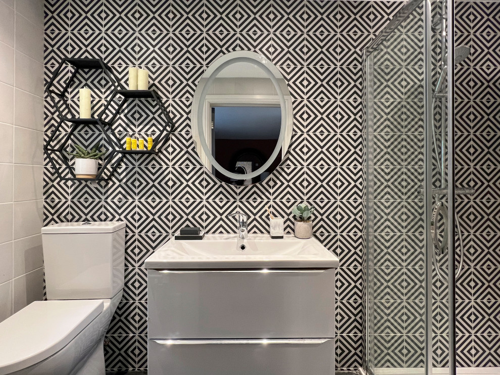 This is an example of a mid-sized country master bathroom in Gloucestershire with beaded inset cabinets, white cabinets, an open shower, a one-piece toilet, black and white tile, marble, cement tiles, an integrated sink, black floor, a sliding shower screen, a single vanity and a floating vanity.