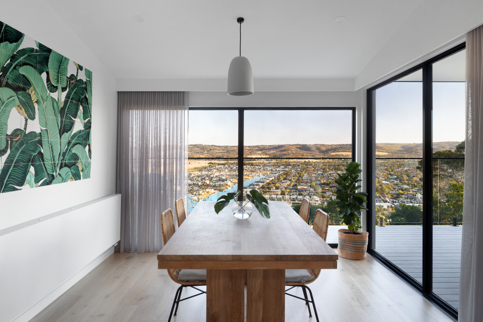 This is an example of a large contemporary open plan dining in Melbourne with white walls, light hardwood floors, beige floor and vaulted.