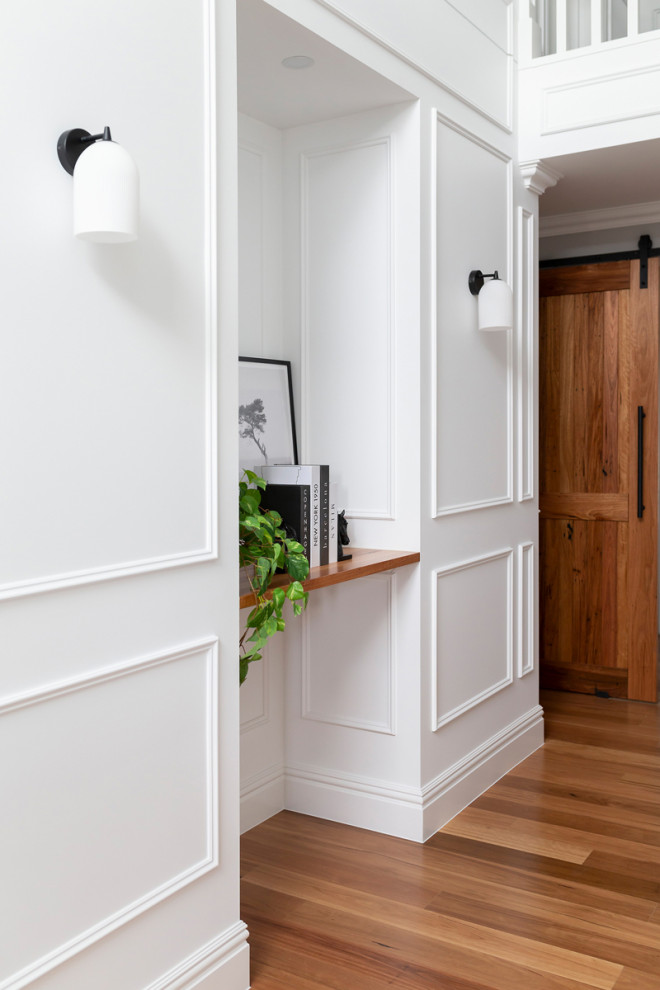Inspiration for a large traditional hallway in Canberra - Queanbeyan with white walls, light hardwood floors and decorative wall panelling.