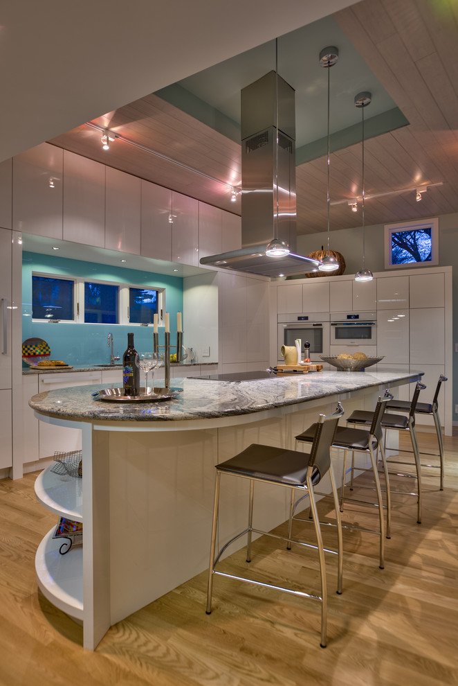 Mid-sized contemporary l-shaped eat-in kitchen in Omaha with an undermount sink, flat-panel cabinets, white cabinets, granite benchtops, blue splashback, stainless steel appliances, light hardwood floors and with island.